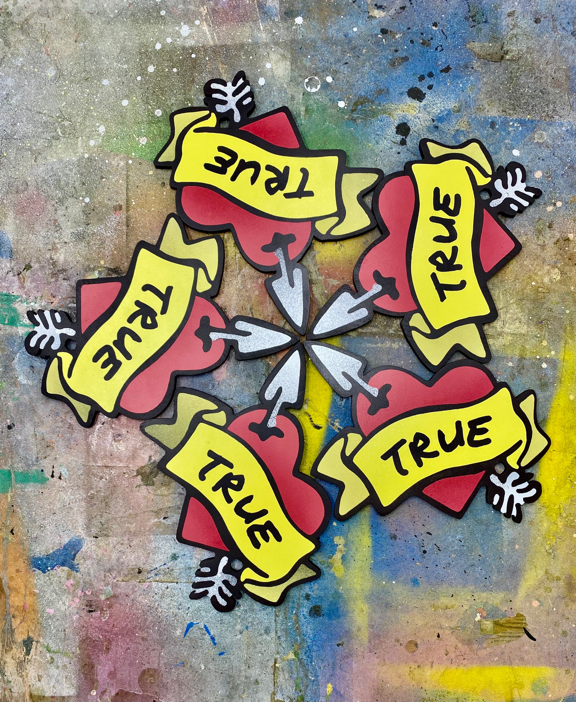 Artistic design of 5 spray painted wooden True Hearts with banners on a textured splattered background
