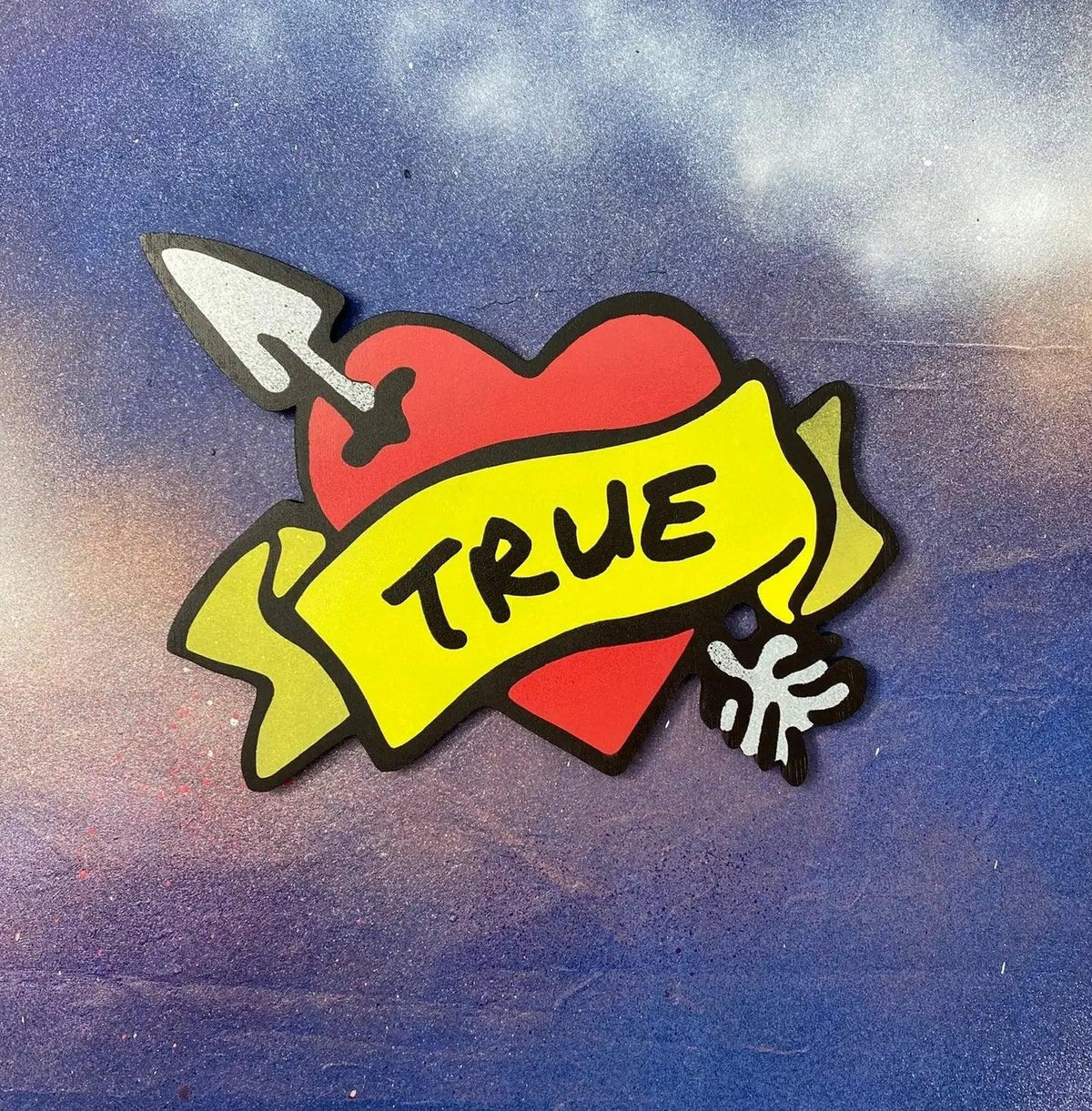 Handmade spray-painted heart wall art with 'TRUE' banner, metallic silver arrow, and vibrant colours on a blue background