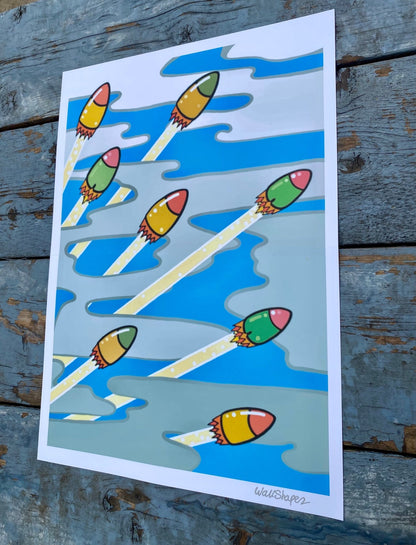 Colorful printed stencil of rockets launching through a cloudy sky, with metallic silver WallShapes signature in the bottom right corner. Photographed in outdoor lighting.