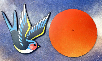 Handmade spray-painted wall art of a blue swallow and orange sun on cloudy blue background, separated.