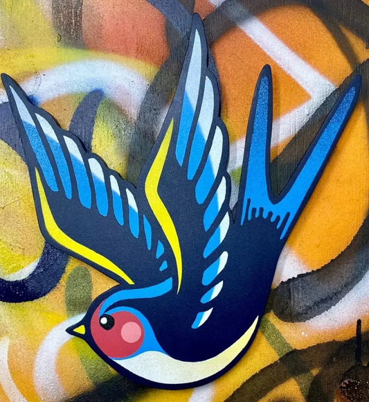 Spray-painted blue swallow wall art with bold yellow and orange graffiti background, handmade by WallShapes.