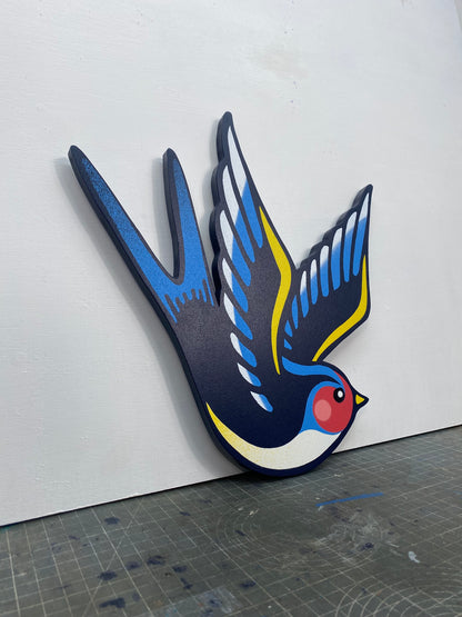 Tattoo inspired, colourful spray painting, painted on a hand-shaped wooden panel displayed on a stencil cutting mat, with a white wall.