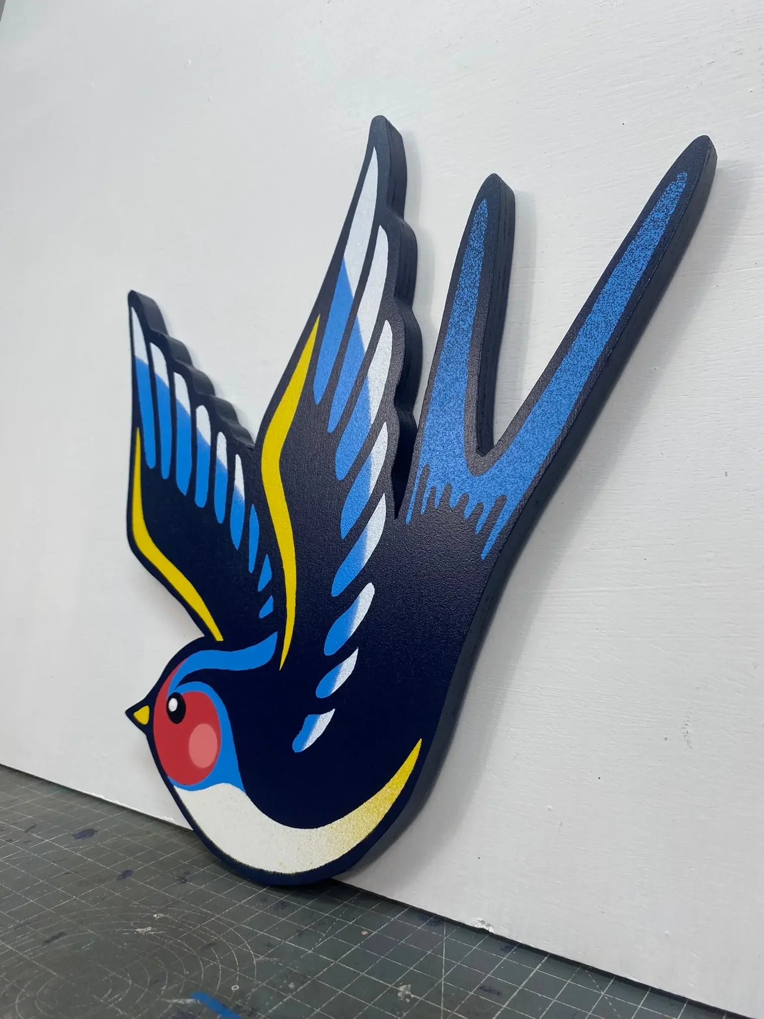 Handcrafted spray-painted blue and yellow swallow wall art on white background, WallShapes UK