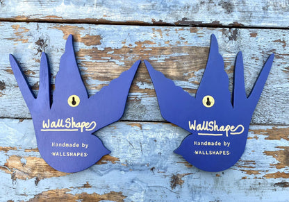 A pair of blue handmade WallShapes decorative swallow bird wall art pieces displayed on a rustic wooden  background.