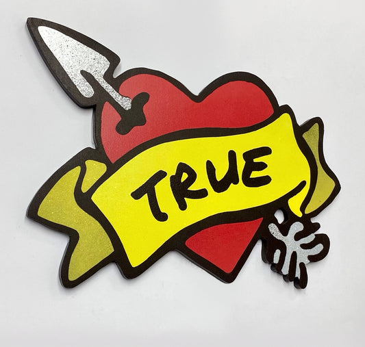 Decorative spray painted, wooden shaped wall art with a red heart, yellow banner, metallic silver arrow and black TRUE text hanging on a white background.