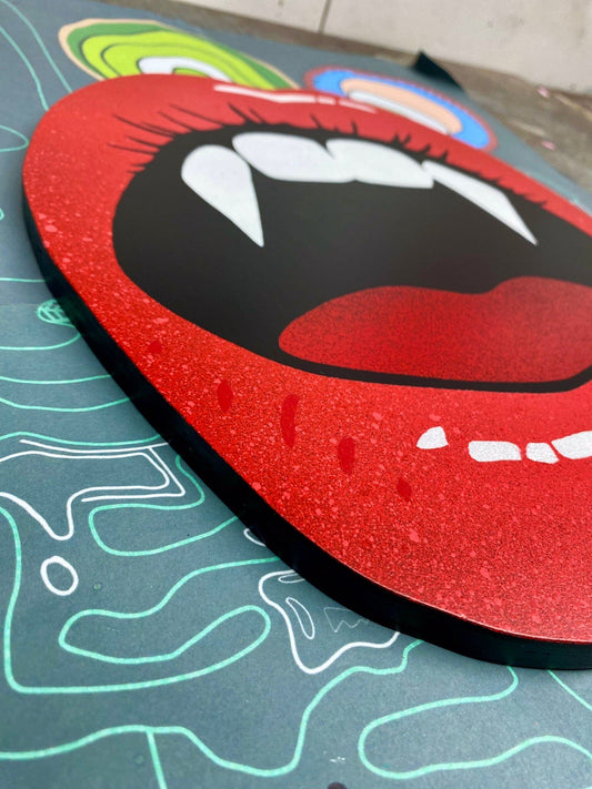 Hand made shaped spray-painting of red lips with vampire fangs on a stencil background.