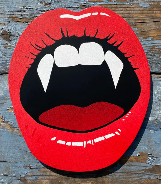 Hand made shaped spray-painting of red lips with vampire fangs on a weathered painted background.
