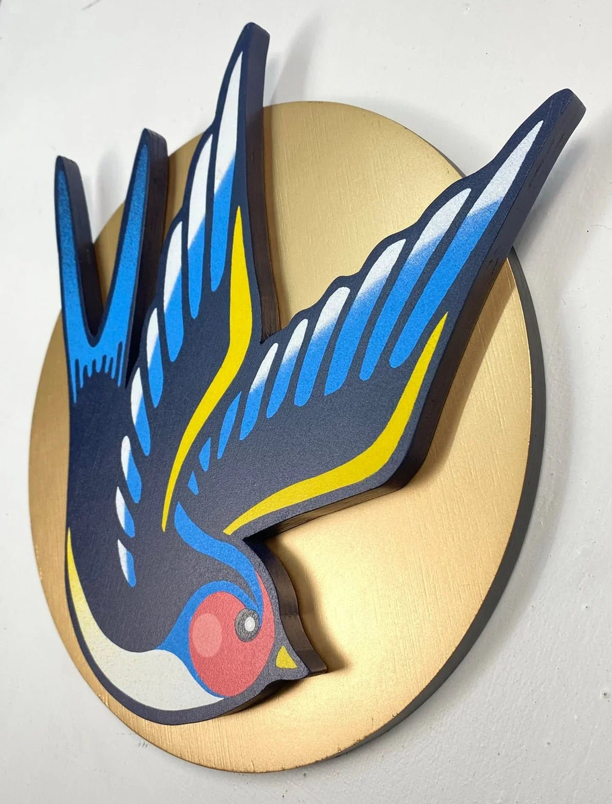 Angled photo of a Handmade colorful swallow bird wall art on gold round background, by WallShapes, UK home decor.