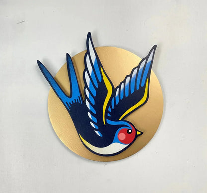 Handmade blue swallow spray-painted wall art on a gold circle, by WallShapes, UK handmade decor.