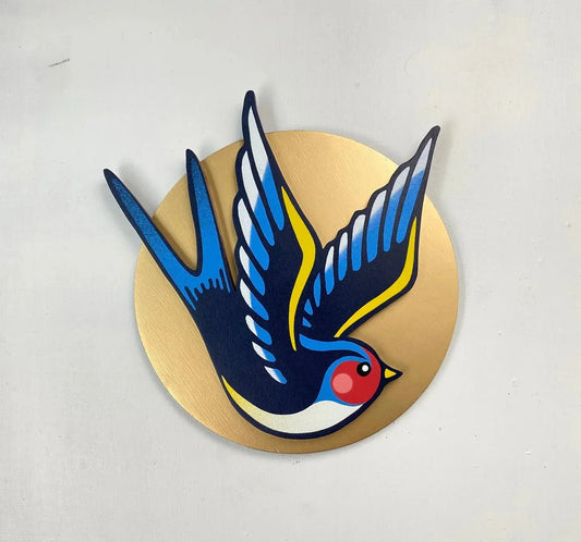 Handmade blue swallow spray-painted wall art on a gold circle, by WallShapes, UK handmade decor.