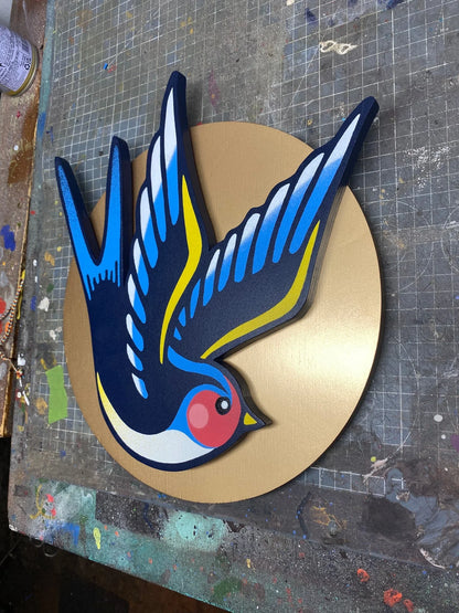Handmade spray-painted wall art of a colorful swallow bird on a gold sun disk, by WallShapes, UK